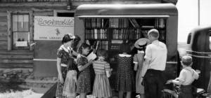 Children browse the exterior shelves of a bookmobile