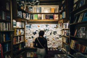 A person looks at a cork board covered in sticky notes in a bookstore.