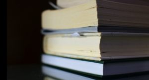 image of a pile of books against a black background https://unsplash.com/photos/fkhesK9SRVU