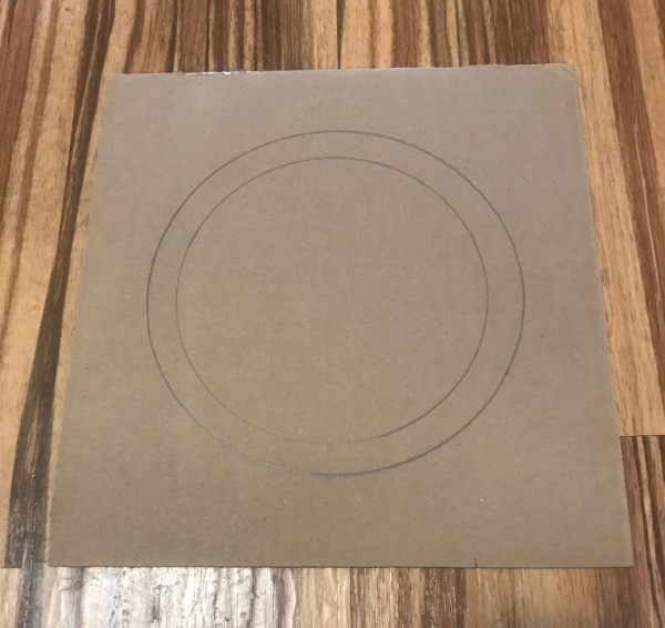 Picture of square piece of cardboard with two circles drawn in the middle