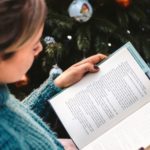 woman reading by the christmas tree for holiday