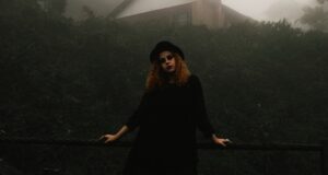 goth woman in black standing against a foggy backdriop