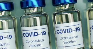 small bottles labeled "covid-19 vaccine" lined up in a row