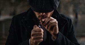 image of a man in a black knit cap lighting a cigarette