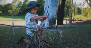little boy building a fire outdoors for kids camping
