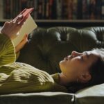 a photo of a woman lying on a couch reading