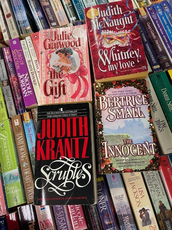array of romance paperbacks: Julie Garwood's the Gift, Judith McNaught's Whitney My Love, Judith Krantz's Scruples, and Bertrice Small's The Innocent