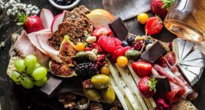 a grazing board full of fresh and dried fruits, assorted meats and cheeses, and other snacks
