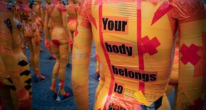 a yellow mannequin with the words "your body belongs to you" taped on its back