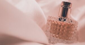 a photo of a perfume bottle against pink fabric