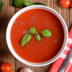 a photo of a bowl of tomato soup surrounded by baby tomatoes