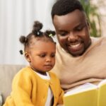 Image of a Black man reading to a child