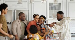 Black family gathered in the kitchen hugging and talking