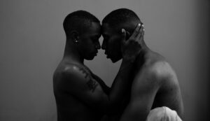 a black and white picture of two Black men holding each other tenderly