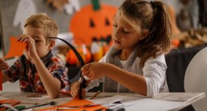 two white children doing halloween crafts at a table