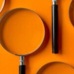 several magnifying glasses arranged against an orange background