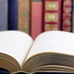a book open in front of other books lined up alongside each other