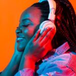 brown-skinned Black woman with box braids wearing headphones and smiling