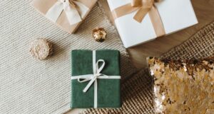 green and white gifts boxes with hold boys on a carpet next to a sequin gold pillow