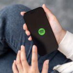 hands holding a cell phone loading the Spotify application
