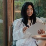 light-skinned Asian woman reading in a lodge