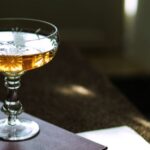a cocktail glass full of liquor, sitting atop a book