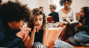 a photo of young women of color discussing books together
