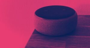 a smart speaker on the edge of a wood surface. a dark red filter is applied to the image