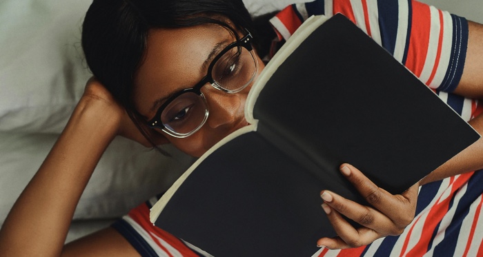 brown-skinned Black woman reading in bed
