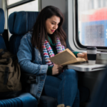 a woman reads on a train and drinks coffee