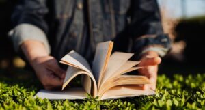 a photo of a book in the grass with an out of focus figure holding it