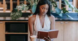brown-skinned Black woman reading a book in a cafe