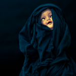 a creepy doll shrouded in black fabric against a black background