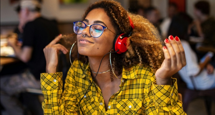 light-skinned Black woman listening to her headphones in a restaurant
