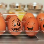 Carton of eggs with faces drawn in sharpie