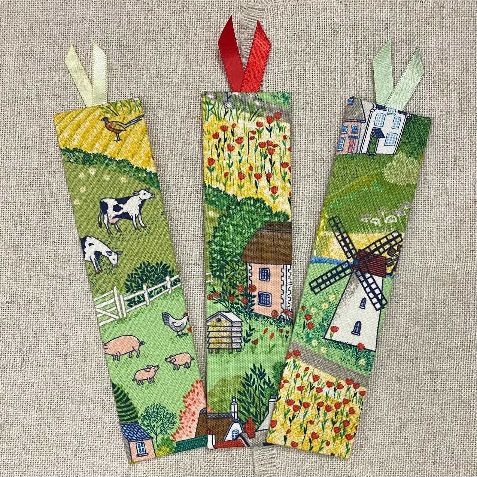a photo of a trio of bookmark featuring illustration of different rural village scenes