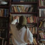 a woman in a hijab searching through shelves in a bookstore