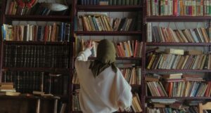 a woman in a hijab searching through shelves in a bookstore