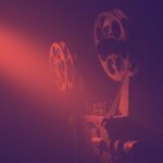 film reels on an old projector with a black and dark red filter applied to the image