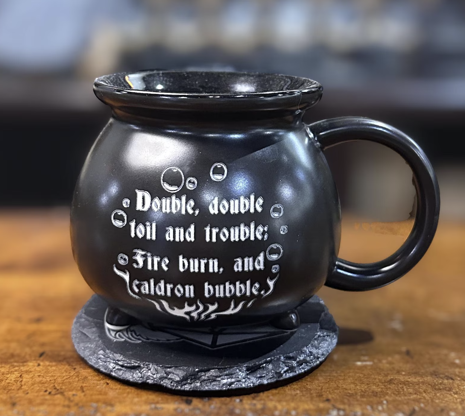 Picture of a black cauldron shaped mug engraved with the words "double double toil and trouble; fire burn, and cauldron bubble" in white