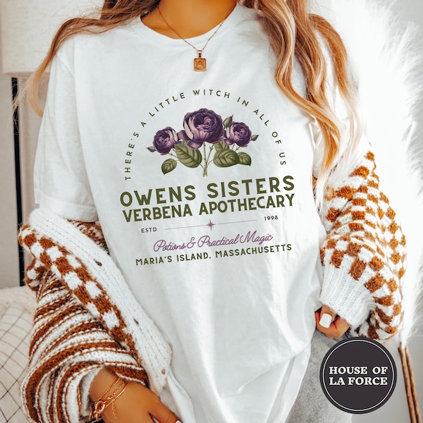 white tshirt with olive green text that reads "Owens Sisters Verbena Apothecary: Potions & Practical Magic. Estd 1998 Maria's Island, Massachusetts" Above the text is a bouquet of purple roses