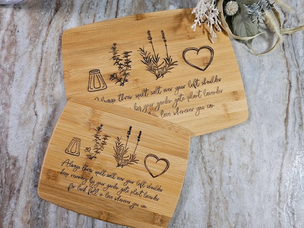 two bamboo cutting boards, one large and one smaller. both contain a salt shaker, a sprig of rosemary, a sprig of lavender, and a heart hovering over a quote from Practical Magic