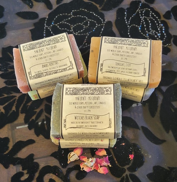 three small piles of handmade soaps with paper labels listing their ingredients