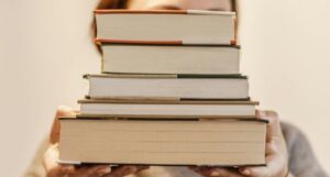 fair-skinned person holding a stack of books