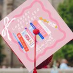 a grad cap topper with an illustration of books and the text "Every chapter led me here"