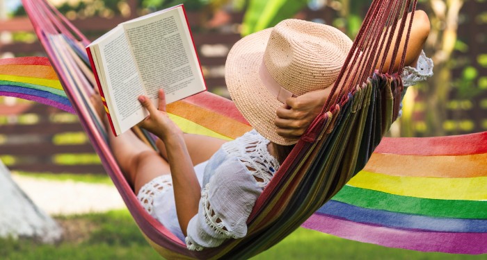 a person reading in a hammock with a rainbow design in the background