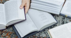 books open on the ground with a hand holding one