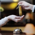 two hands exchanging a key in a hotel lobby/reception area
