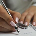 light tan skin hands with a manicure writing with a fountain pen in a notebook