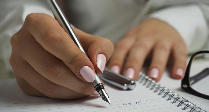 light tan skin hands with a manicure writing with a fountain pen in a notebook